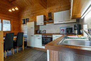 a kitchen with white appliances and wooden walls at Waldsiedlung - Haus 11 in Senftenberg