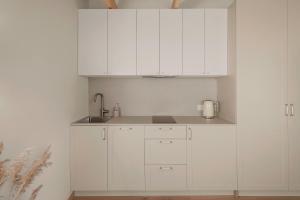 a white kitchen with white cabinets and a sink at Sava Nida in Neringa +5 photos