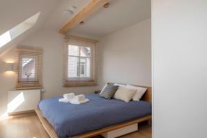 a bedroom with a bed with blue sheets and two windows at Sava Nida in Neringa