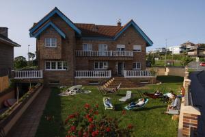 a group of people sitting in lawn chairs in front of a house at Gijon Surf Hostel in Gijón