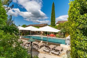 a pool with chairs and umbrellas next to a house at Mas Escombelle in Barjac