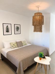 a bedroom with a bed with a table and a chandelier at Departamento céntrico funcional I Punto Alquiler in Santiago del Estero