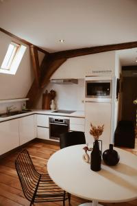 a kitchen with a white table and a table and chairs at B&B De Mout in Diest