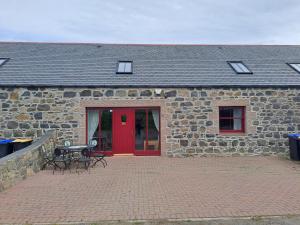 a stone building with a red door and a patio at Glen Lyon in Inverurie