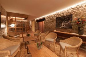 a restaurant with chairs and tables and a stone wall at Hotel Finca Llongarriu - Only Adults in Vall de Bianya