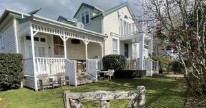 a white house with a porch and a yard at Rose Lodge Bed & Breakfast in Tirau