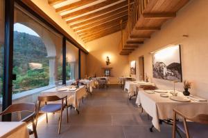 a restaurant with tables and chairs and a large window at Hotel Finca Llongarriu - Only Adults in Vall de Bianya