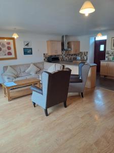 a living room with a couch and chairs and a kitchen at Glen Lyon in Inverurie