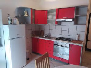 a kitchen with red cabinets and a white refrigerator at Apartman Cvitan in Zaton