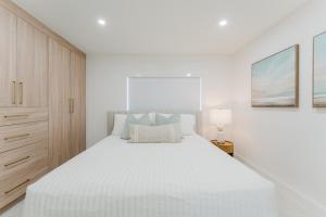 a white bedroom with a large white bed and a cabinet at Villa Verde - Boca Pool & Beach Walk in Boca Raton