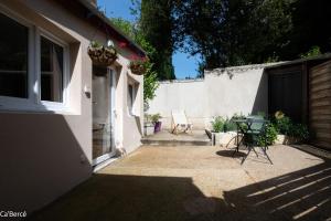a patio with a table and chairs next to a house at Ca'Bercé Studio équipé in Château-du-Loir