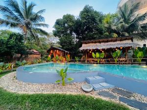 a resort swimming pool with a restaurant in the background at The Elephant Next-Door in Udawalawe