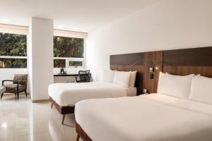 a hotel room with two beds and a desk at San Simon Hotel Pereira By Soratama in Pereira