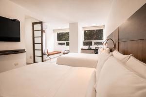 a bedroom with two beds and a flat screen tv at San Simon Hotel Pereira By Soratama in Pereira