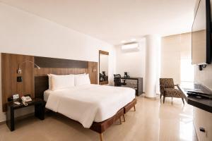 a bedroom with a large white bed and a television at San Simon Hotel Pereira By Soratama in Pereira