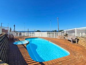 a swimming pool on a patio with a white fence at Scottburgh Views 707 Seafront Apartment in Scottburgh