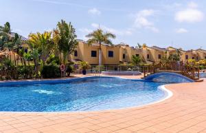 a swimming pool in a resort with palm trees and buildings at Meloneras in Meloneras