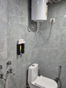 a bathroom with a toilet and a dispenser on the wall at Blueberry Premium Hotel in Greater Noida +19 photos