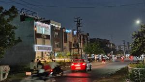 a red car driving down a city street at night at Blueberry Premium Hotel in Greater Noida