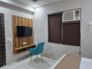 a bedroom with a tv and a blue chair at Blueberry Premium Hotel in Greater Noida