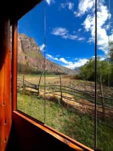 a window view of a field with a fence and mountains at Awki Wasi - Sacred Valley in Lamay +22 photos