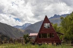 a small house in a field with mountains in the background at Awki Wasi - Sacred Valley in Lamay