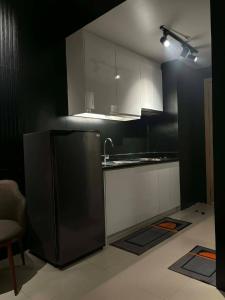 a kitchen with black and white cabinets and a refrigerator at JJ Staycation Tower 2 in Manila