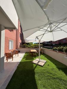 a patio with a large white umbrella on the grass at Effealatapartments - L'Oasi del Forte in Forte dei Marmi