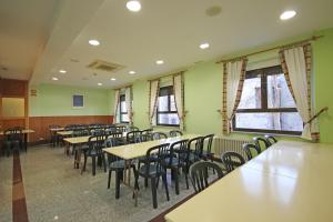 un comedor con mesas, sillas y ventanas en Residencia Universitaria Cum Laude, en Salamanca