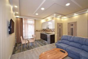 a living room with a blue couch and a kitchen at Рядом с метро in Yerevan