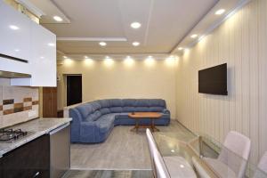 a living room with a blue couch and a tv at Рядом с метро in Yerevan