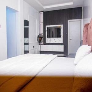 a bedroom with a bed with a tv on the wall at Tomfrank Hotel in Ado