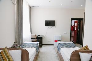 a hotel room with two beds and a tv at Apple Hostel Bishkek in Bishkek