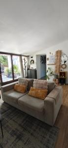 a brown couch in a living room with windows at Gîte des Bartavelles in Saint-Didier