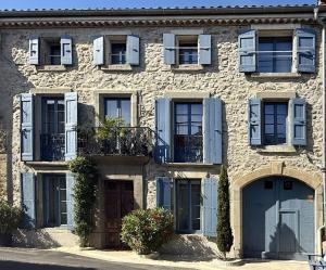 a stone building with blue doors and windows at L'Oiseau Bleu ROLLIER in Roubia