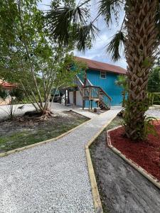 a palm tree and a blue building with a staircase at Sandy Pines Perch - Your Indian River Dock Life Base Camp in Sebastian