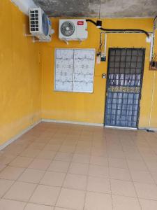 a room with a yellow wall with a fan and a window at Tipika Room Pasir Pekan in Tumpat
