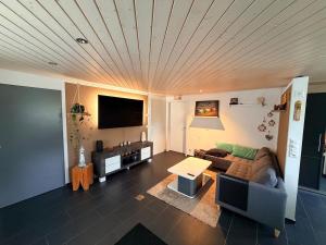 a living room with a couch and a flat screen tv at Modern apartment with garden in Lostorf