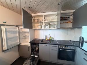 a kitchen with white cabinets and an open refrigerator at Modern apartment with garden in Lostorf +10 photos