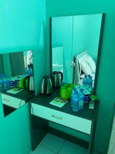 a bathroom counter with a mirror and water bottles on it at Wind Stay in Male City