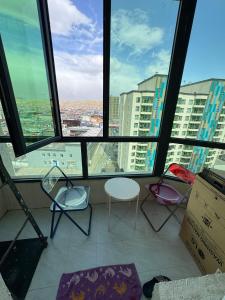 a room with three chairs and large windows at Cozy Apartment newly furnished in Ulaanbaatar