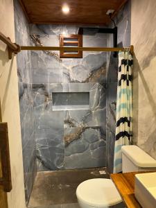 a bathroom with a toilet and a stone wall at Casa bambu atins in Atins
