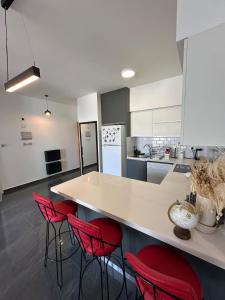 a kitchen with a counter and four red chairs at Hunz Homes in Ayii Trimithias