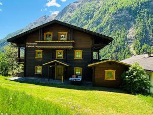 a large wooden house with mountains in the background at Ferienhaus Unterkircher-Wallner in Heiligenblut +17 photos