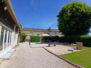 a yard with benches and a building with a tree at La Vieille Fromagerie in Brux