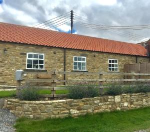 ein Steinhaus mit einem Zaun davor in der Unterkunft Brooksides Byre Durham Country Cottage in Durham