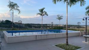 a swimming pool with palm trees in a resort at Apartamento confortável in Manaus