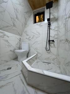 a white bathroom with a tub and a toilet at NerNeri Cottage Martvili in Martvili