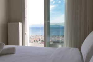 a bedroom with a bed and a large window at Nayra View & Spa in Kavála