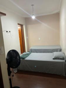 two beds in a room with a fan at Pousada Miriam in Limeira +6 photos